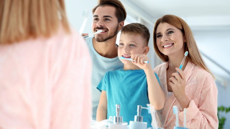 Smiling family brushing teeth together to prevent cavities in kids – Downtown Plaza Dental